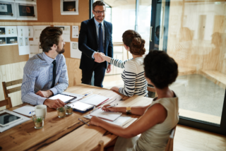 Strategic account manager shaking hands with a customer during a meeting, highlighting trust and relationship building.