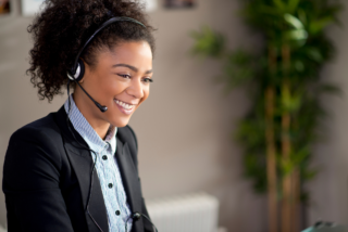 Smiling customer service representative wearing headset, exemplifying empathy in a professional setting.